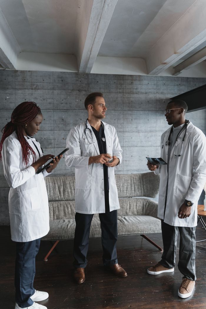 Three healthcare professionals in discussion at a hospital setting.